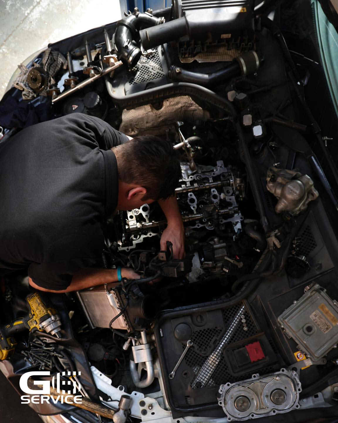 G6 Service technician working deep in an engine bay during a rebuild